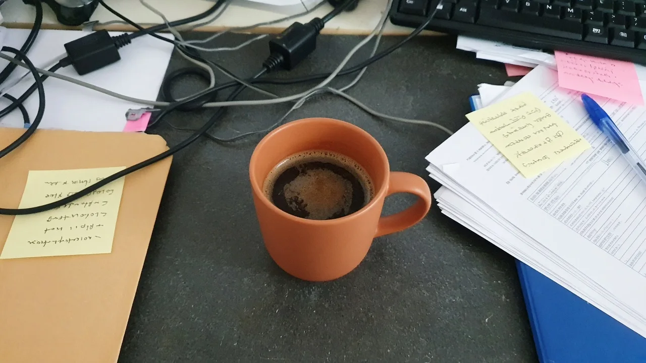Unbranded terracotta coffee mug on a cluttered office desk before AI background change