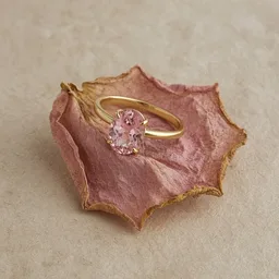Unbranded gold ring with a pink stone on a dried rose petal